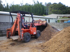 John in small bulldozer picking up nut husks