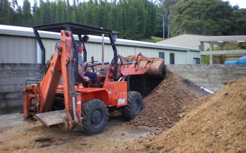 John in small bulldozer picking up nut husks